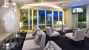A modern lounge area with sofas and armchairs, large windows with city views, and a flat-screen TV mounted on the wall. - The Carrington Hotel Shepparton (Shepparton)