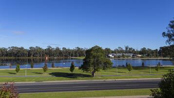 A view of a lake with a road in the foreground and trees in the background.