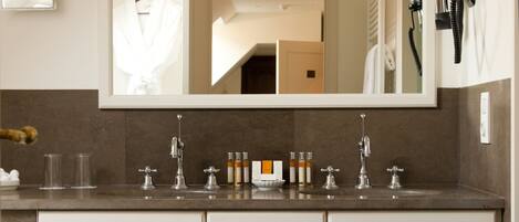 Une salle de bain avec un grand miroir, un lavabo doté de plusieurs robinets et un porte-serviettes.