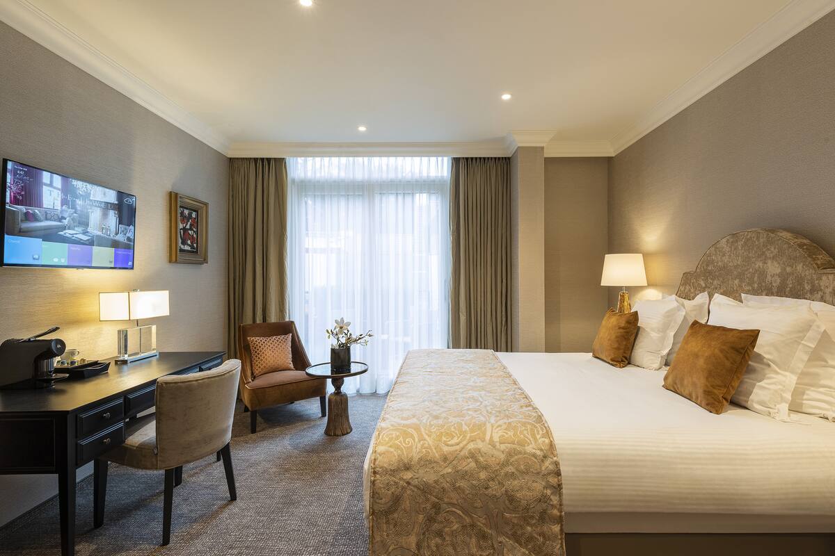 Een hotelkamer met een bed, een bureau, een stoel, een televisie en een raam met gordijnen.