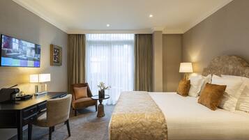 A hotel room with a bed, a desk, a chair, a TV, and a window with curtains.
