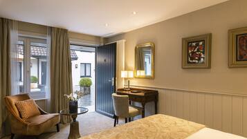 Hotelkamer met een bed, bureau, stoel, lamp en uitzicht.