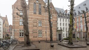 A historic building with a brick facade, large windows, and a prominent tower. -  Dukes’ Palace Residence – by Dukes’ Hotel Collection (Bruges)