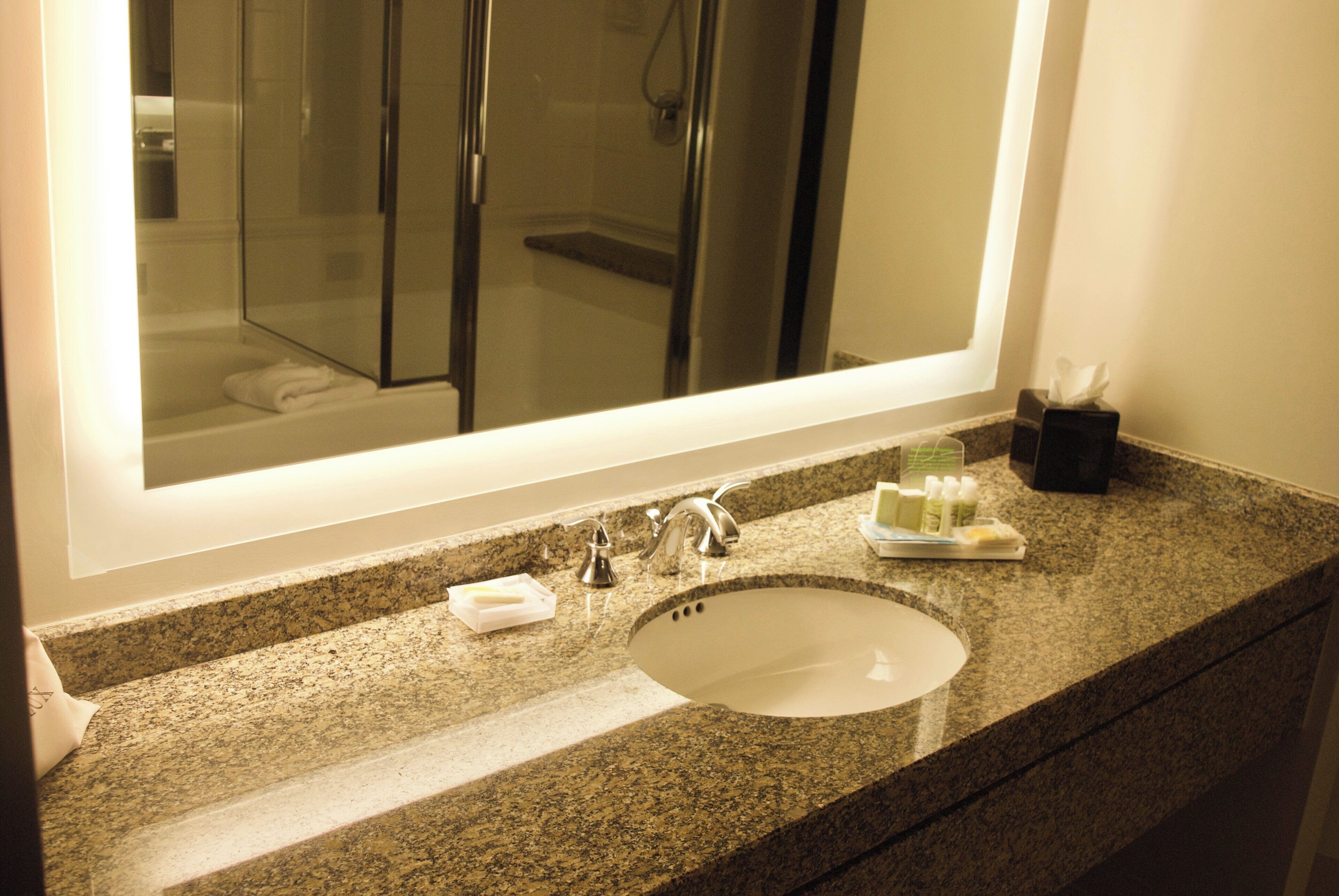 A bathroom with a granite countertop, a sink, a mirror, and a towel rack.