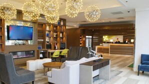 Un vestíbulo de hotel con área de descanso, una recepción y un televisor.