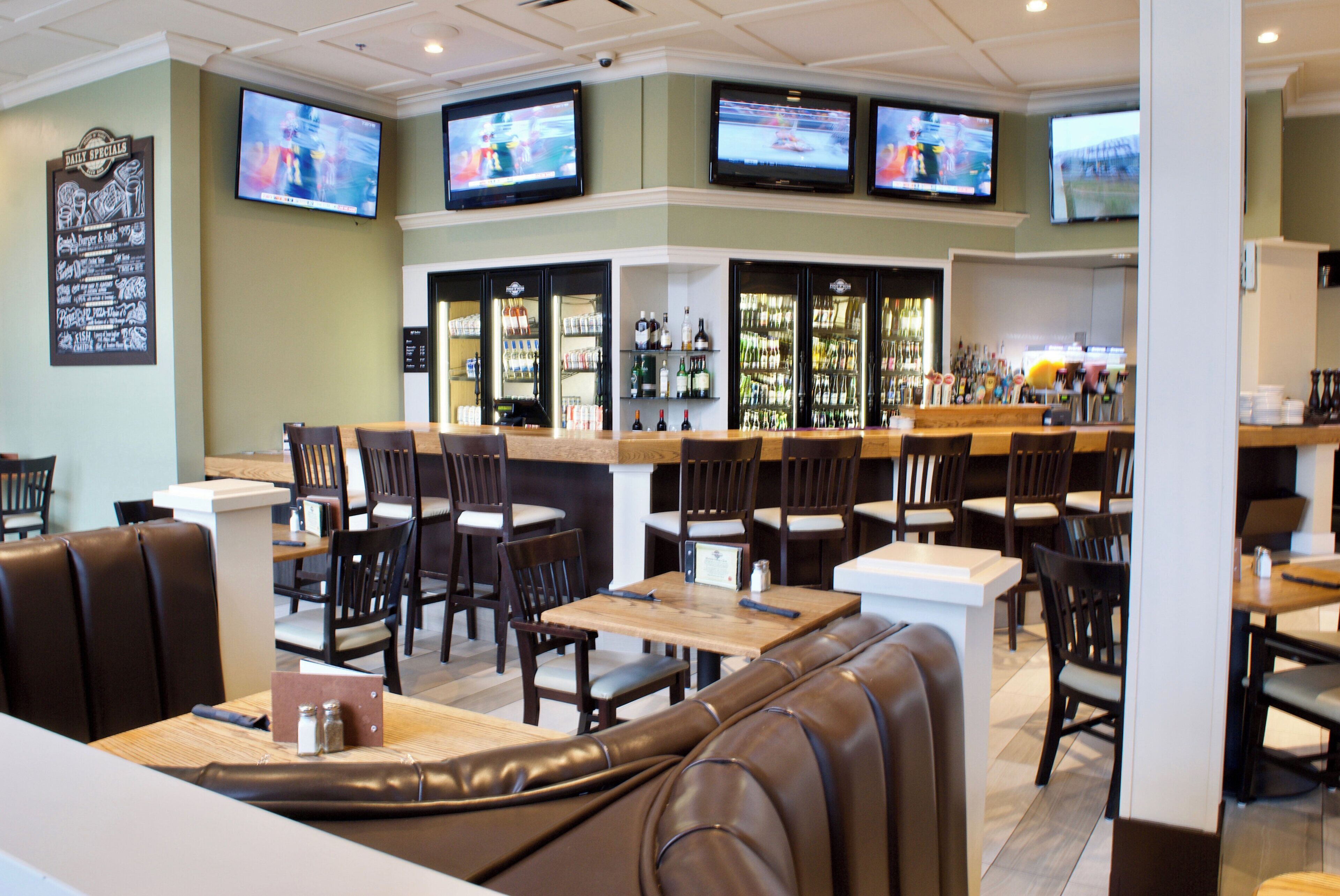 A restaurant with multiple seating areas, including booths and tables, and a bar with a variety of bottles.