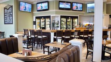 A restaurant with multiple seating areas, including booths and tables, and a bar with a variety of bottles.
