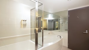 A modern bathroom with a glass-enclosed jacuzzi, a large mirror, and a dark door. - Holiday Inn Vancouver Airport- Richmond by IHG (Richmond)