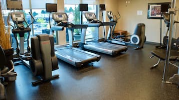 Un gimnasio con cintas de correr, elípticas y bicicletas estáticas.