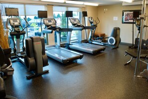 Un gimnasio con cintas de correr, elípticas y bicicletas estáticas.