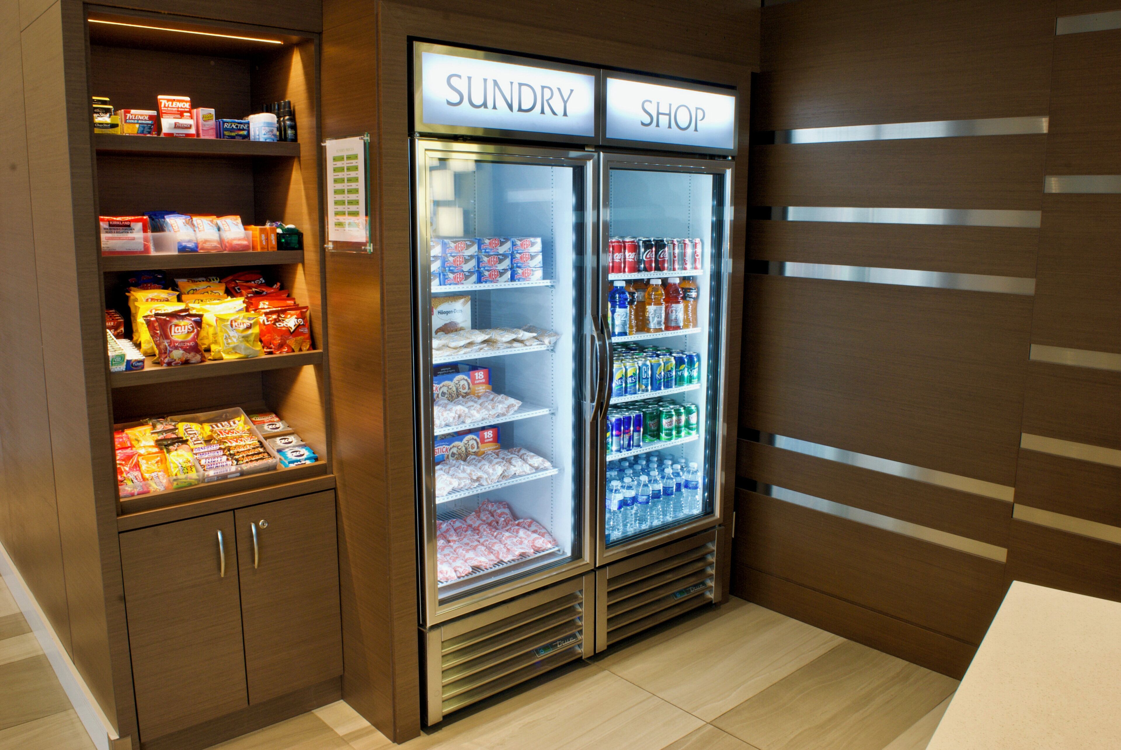 Una tienda de conveniencia con estantes llenos de bocadillos y un refrigerador con bebidas.