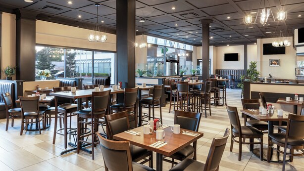 Un restaurante espacioso con techos altos, iluminación moderna y grandes ventanales con vistas al exterior.