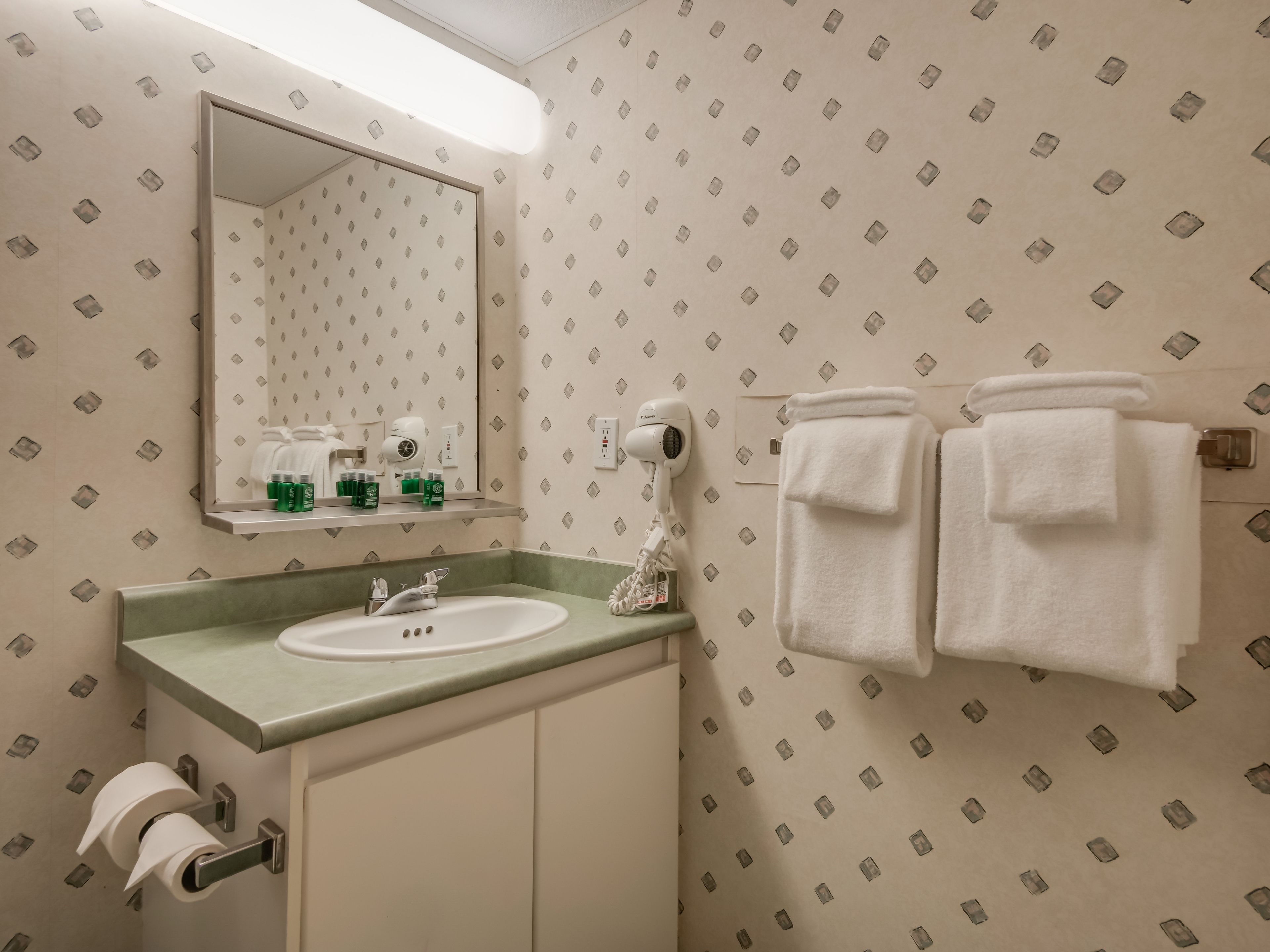 A bathroom with a sink, mirror, towel rack, and toiletries.