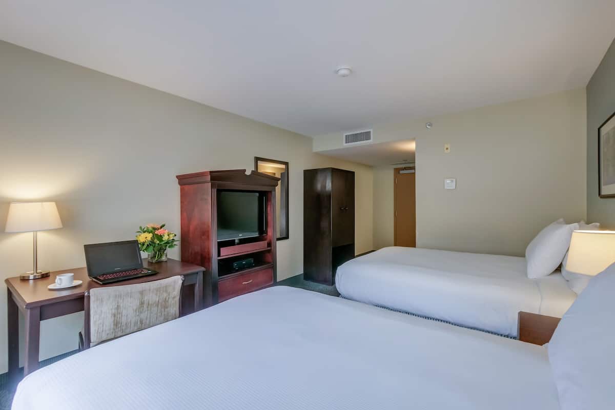 A hotel room with a bed, a desk with a laptop, a TV, and a wardrobe.