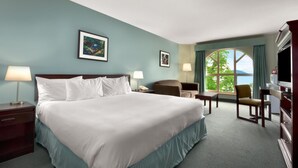 Une chambre d’hôtel avec un grand lit, deux fauteuils, un bureau et un téléviseur.