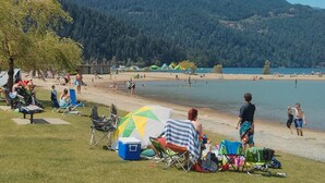 Une plage avec des gens, des tentes et une montagne en arrière-plan.