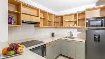Una cocina moderna con armarios empotrados de madera, un refrigerador de acero inoxidable, un microondas y un lavavajillas.