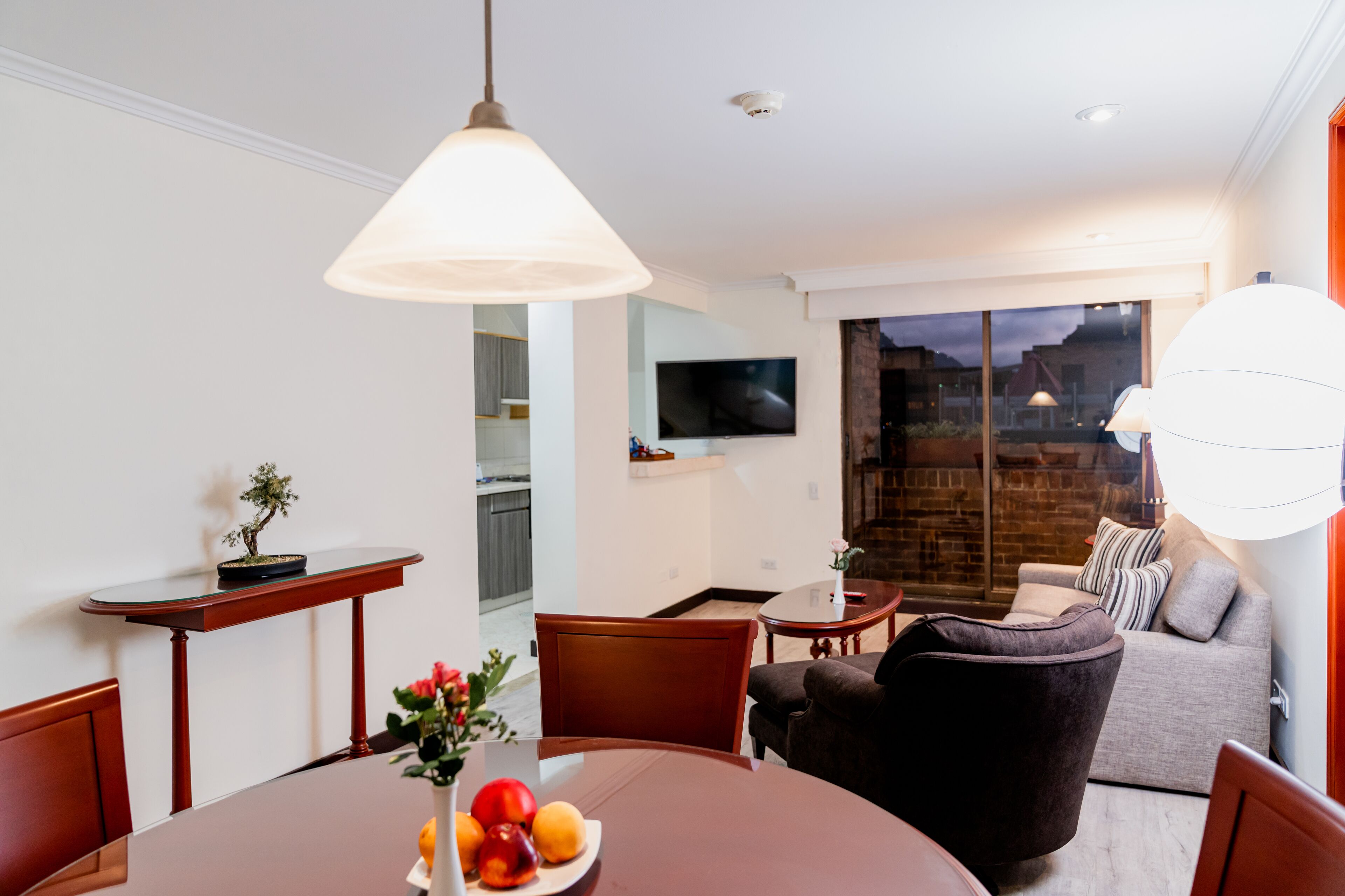 Un salon moderne comprenant une table à manger, des chaises, un canapé et un téléviseur fixé au mur.