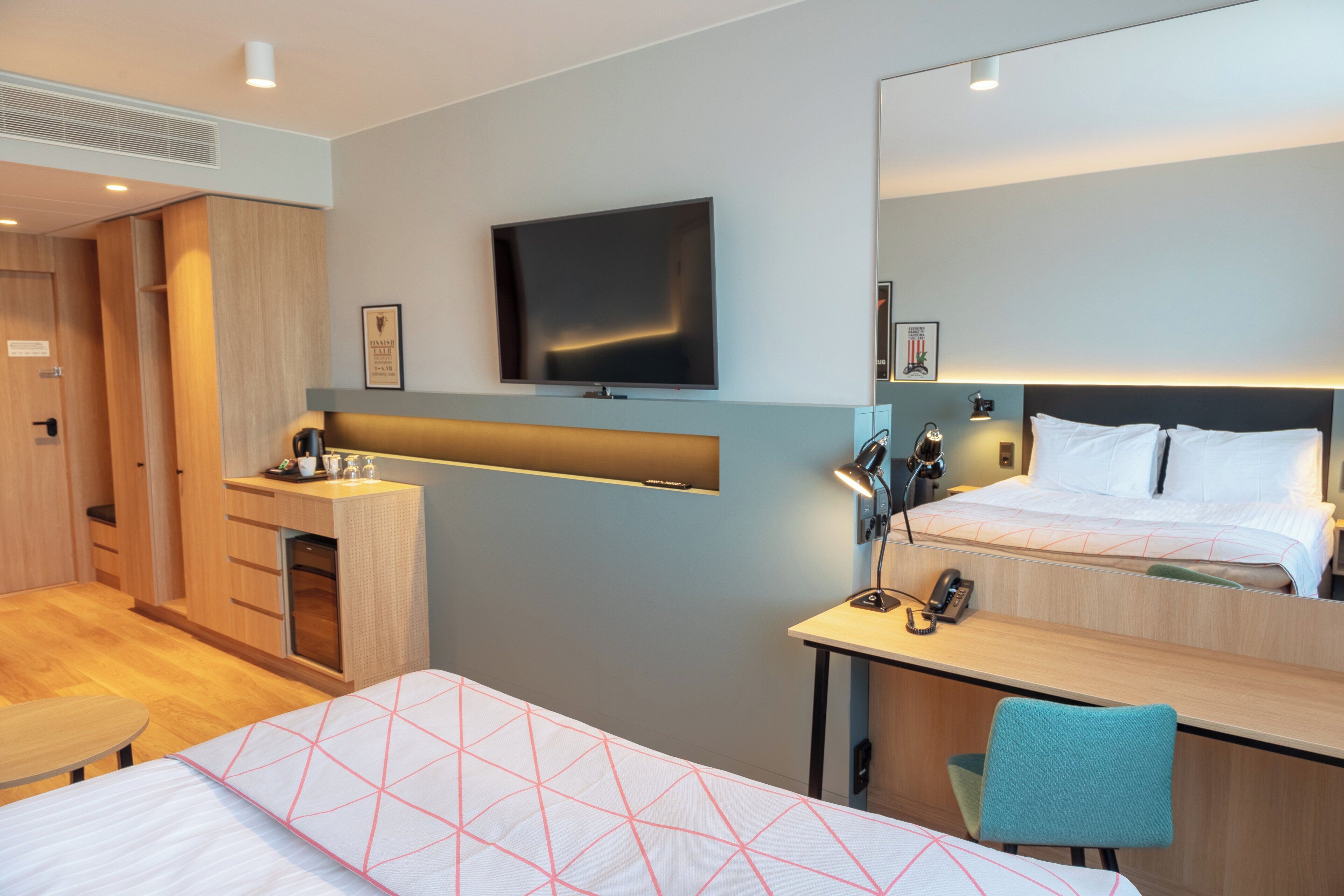 Una habitación de hotel con una cama, un escritorio, una silla, un televisor y un armario.