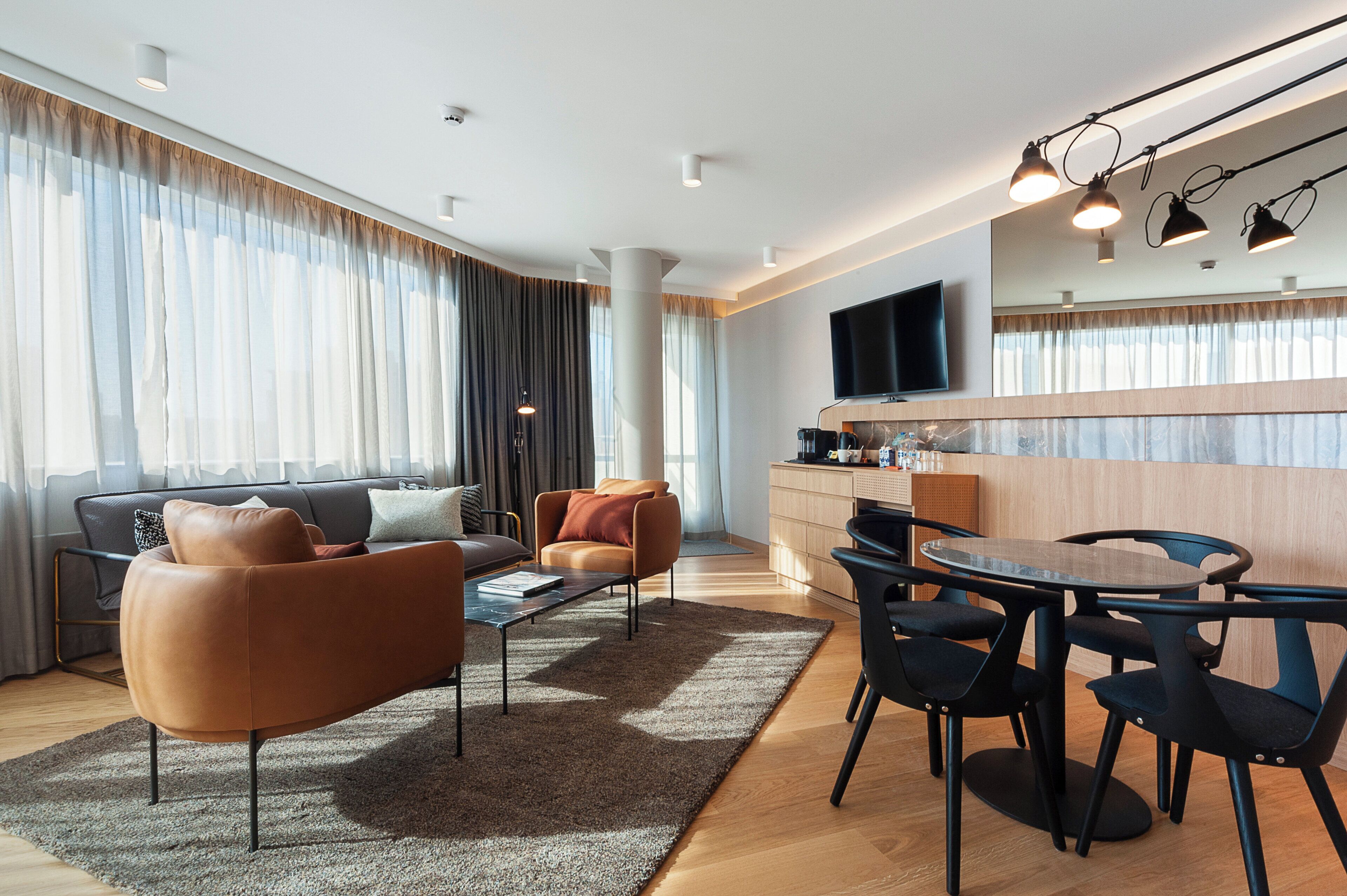 Una sala de estar moderna con sofá, mesa de centro y comedor con sillas.