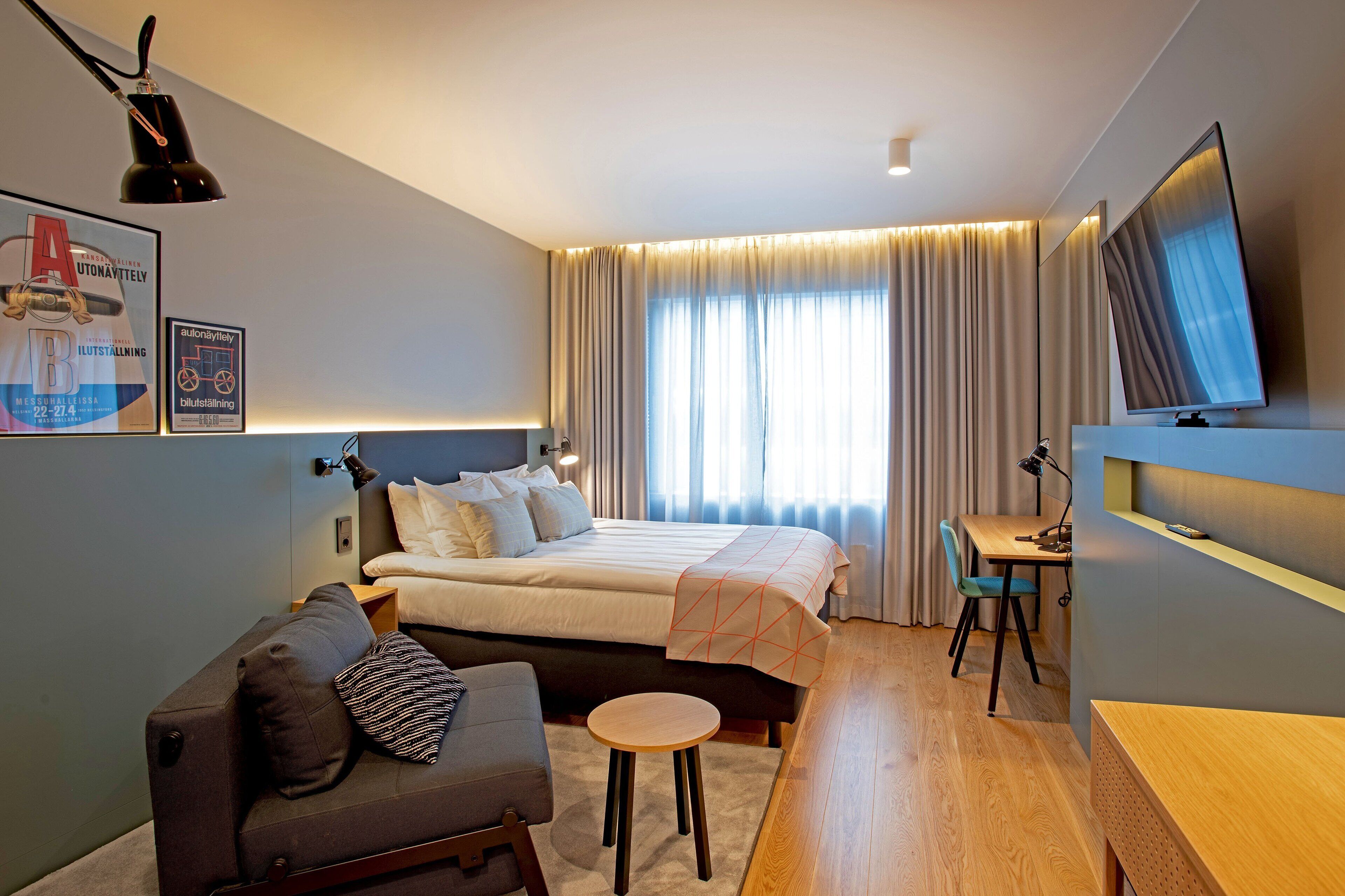 Una camera d'albergo moderna con un letto, un divano, una scrivania e una televisione.
