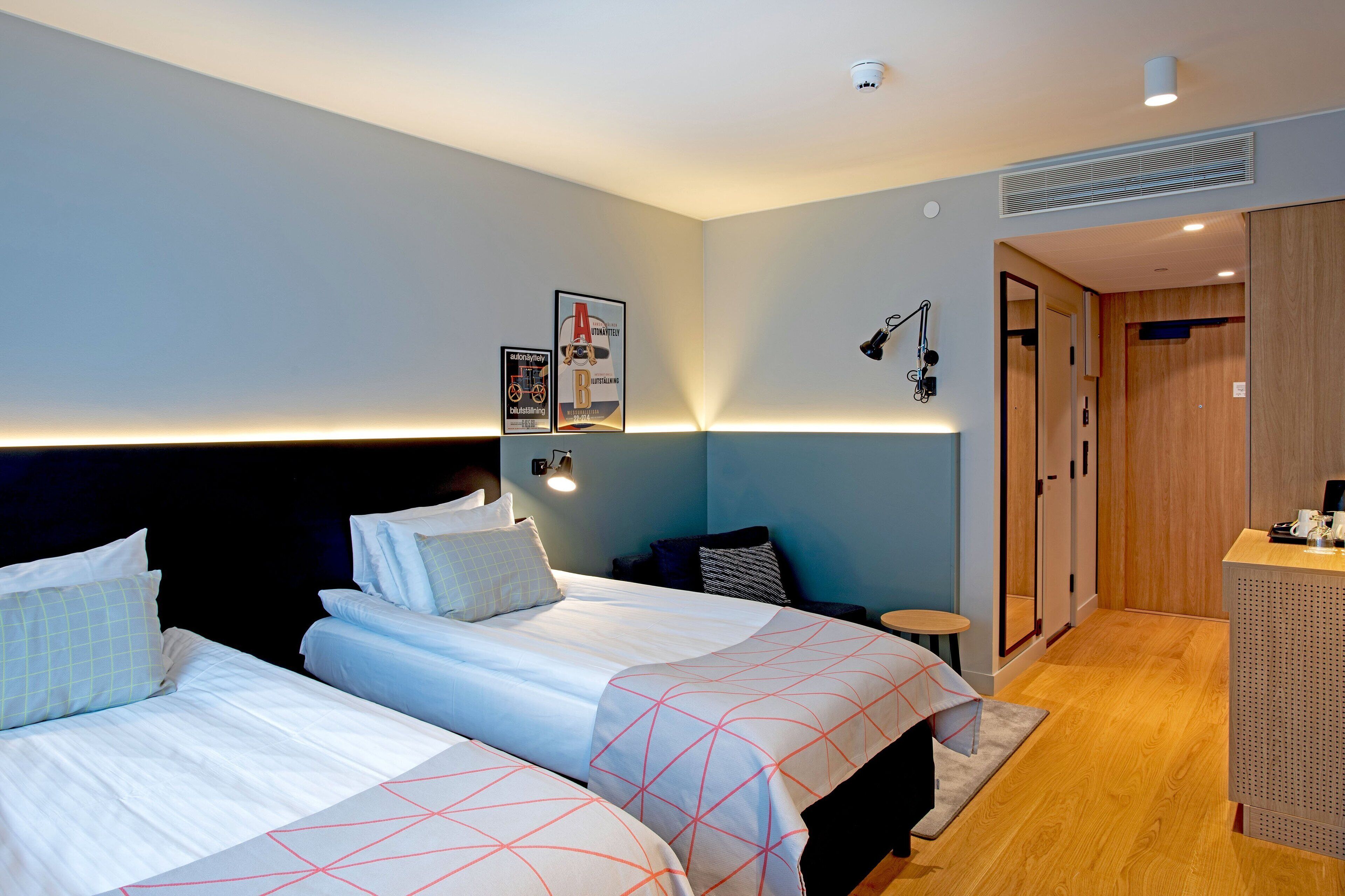 A hotel room with two beds, a desk, and a wardrobe.