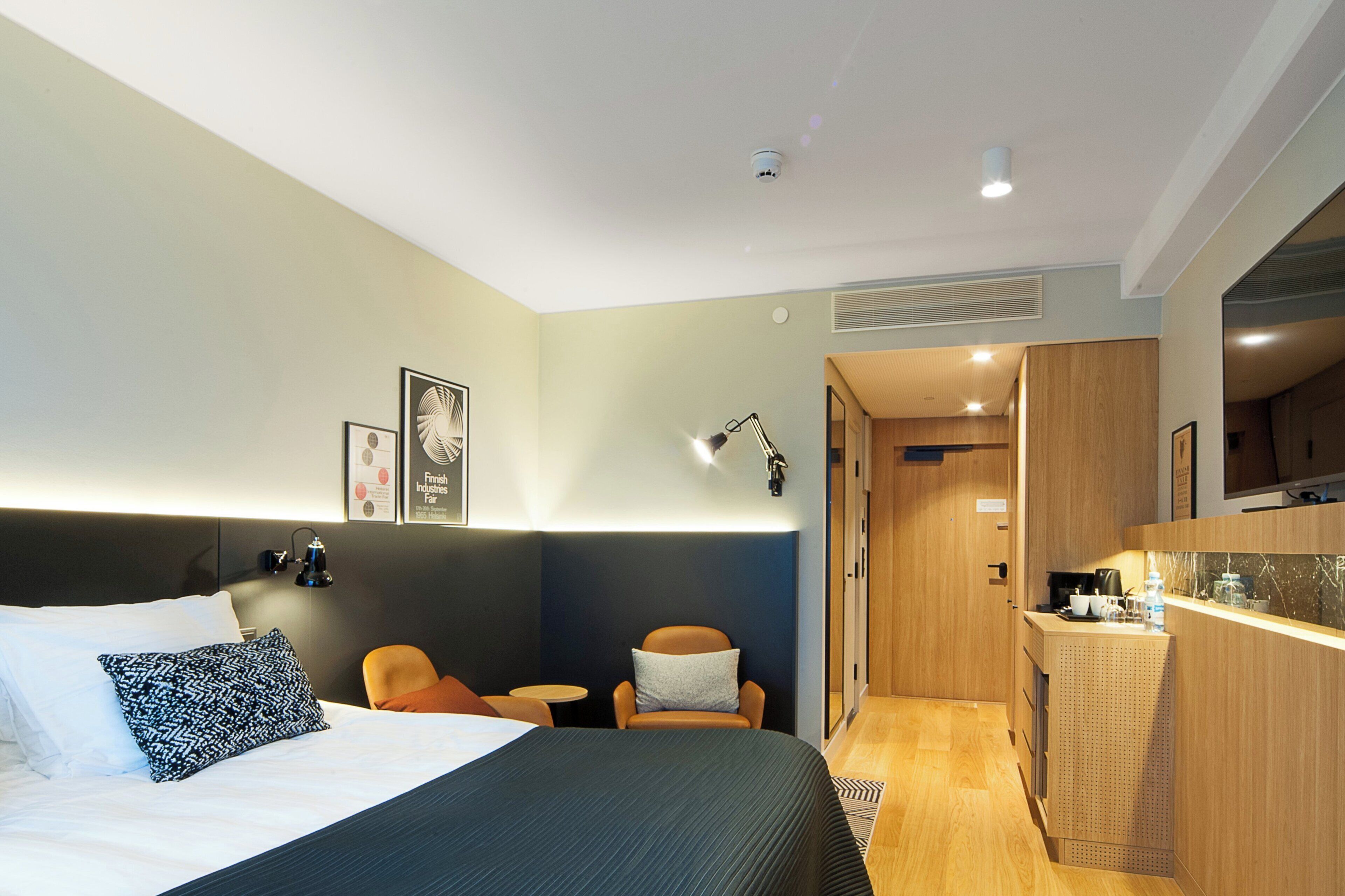 Habitación de hotel con cama, escritorio, silla y kitchenette.