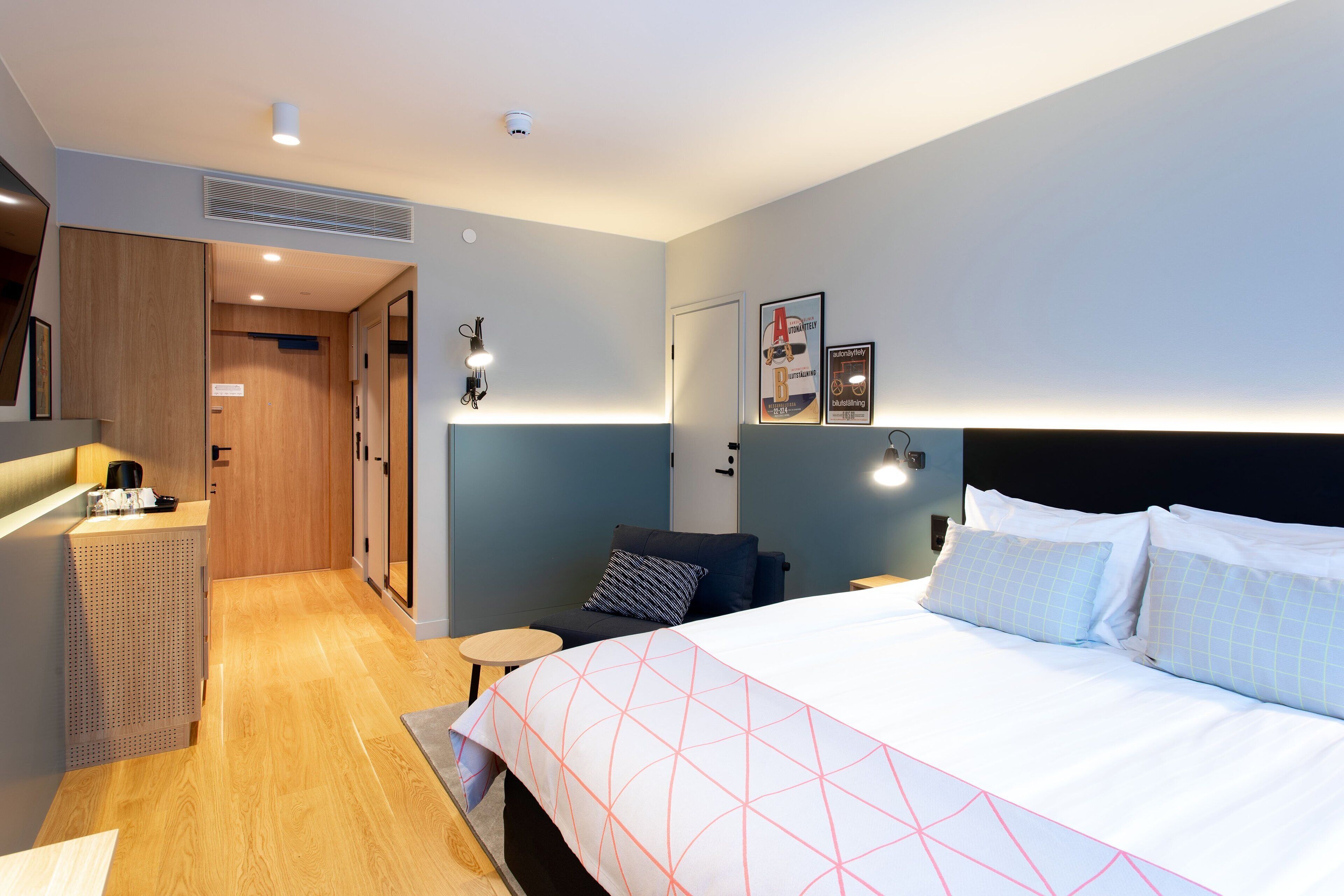 Una habitación de hotel moderna con una cama grande, un escritorio y un armario.