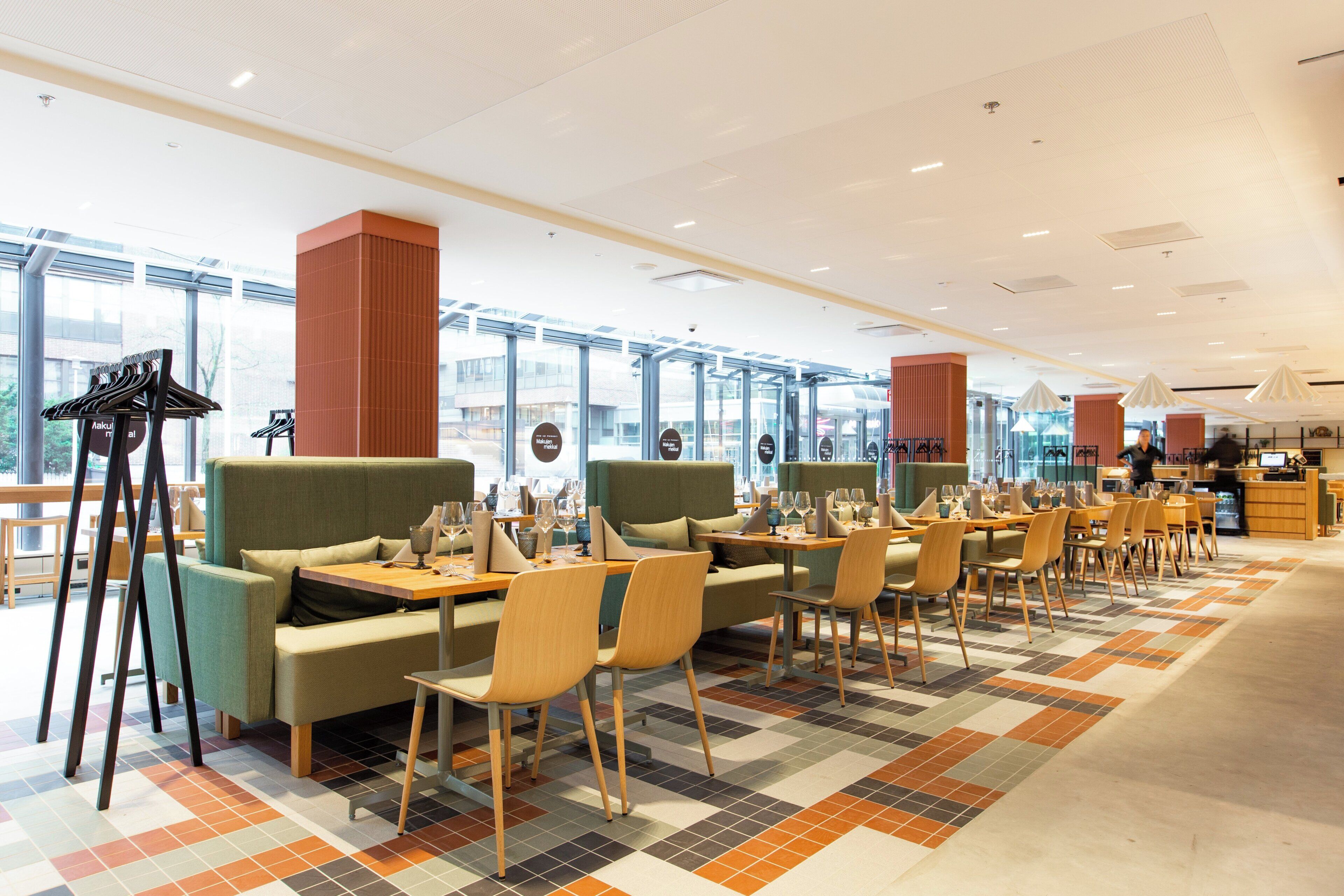 Un restaurante moderno con mesas altas, asientos acolchados y grandes ventanales.
