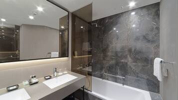 Une salle de bain moderne avec un grand miroir, deux lavabos, une baignoire et des murs en marbre.