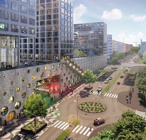 Moderni kaupunkikatu, jossa on jalankulkijoiden käytävä, kiertoliittymä ja rakennus, jonka ainutlaatuinen julkisivu on koristeltu pyöreillä ikkunoilla.