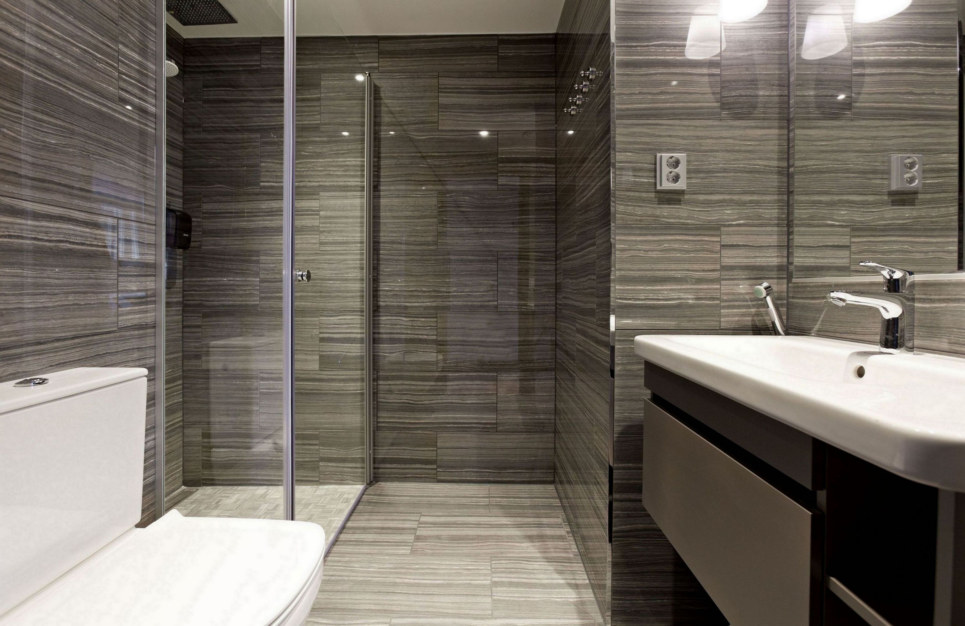 A modern bathroom with a glass-enclosed shower, a white sink, and a large mirror.