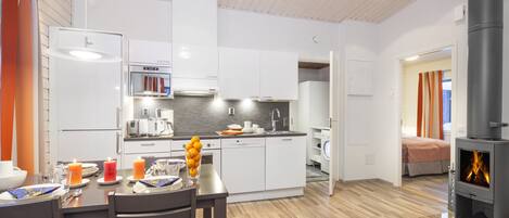 Una cocina moderna con armarios blancos, horno empotrado e isla central con lavamanos.