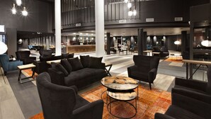A modern lobby with black sofas, a coffee table, and hanging pendant lights. - Holiday Club Kuusamon Tropiikki (Kuusamo)