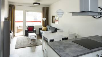 A modern kitchen with a built-in stove, white cabinetry, and a dining area with a white table and chairs.