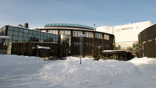 A modern building with a curved glass facade and a flat-roofed structure with a sign. - Holiday Club Kuusamon Tropiikki (Kuusamo)