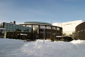 A modern building with a curved glass facade and a flat-roofed structure with a sign. - Holiday Club Kuusamon Tropiikki (Kuusamo)