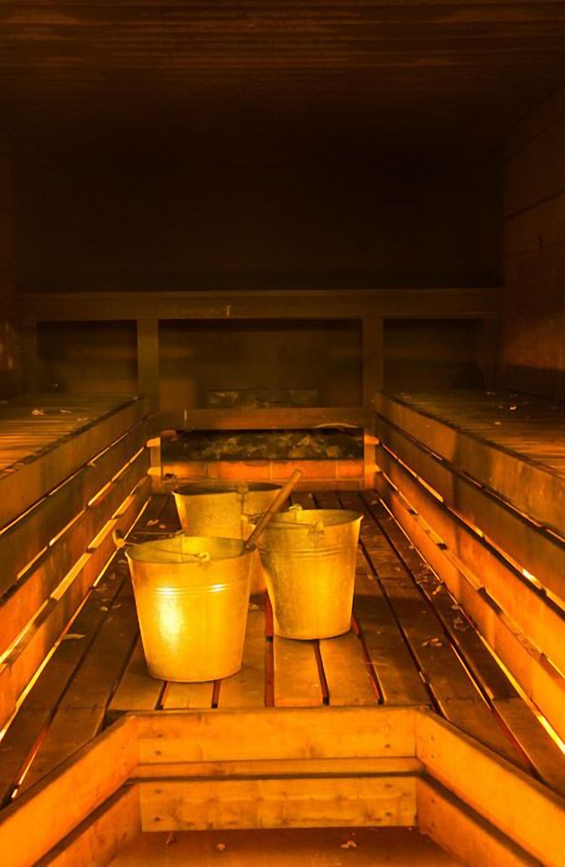 A sauna with wooden benches and metal buckets.