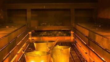 A sauna with wooden benches and metal buckets.