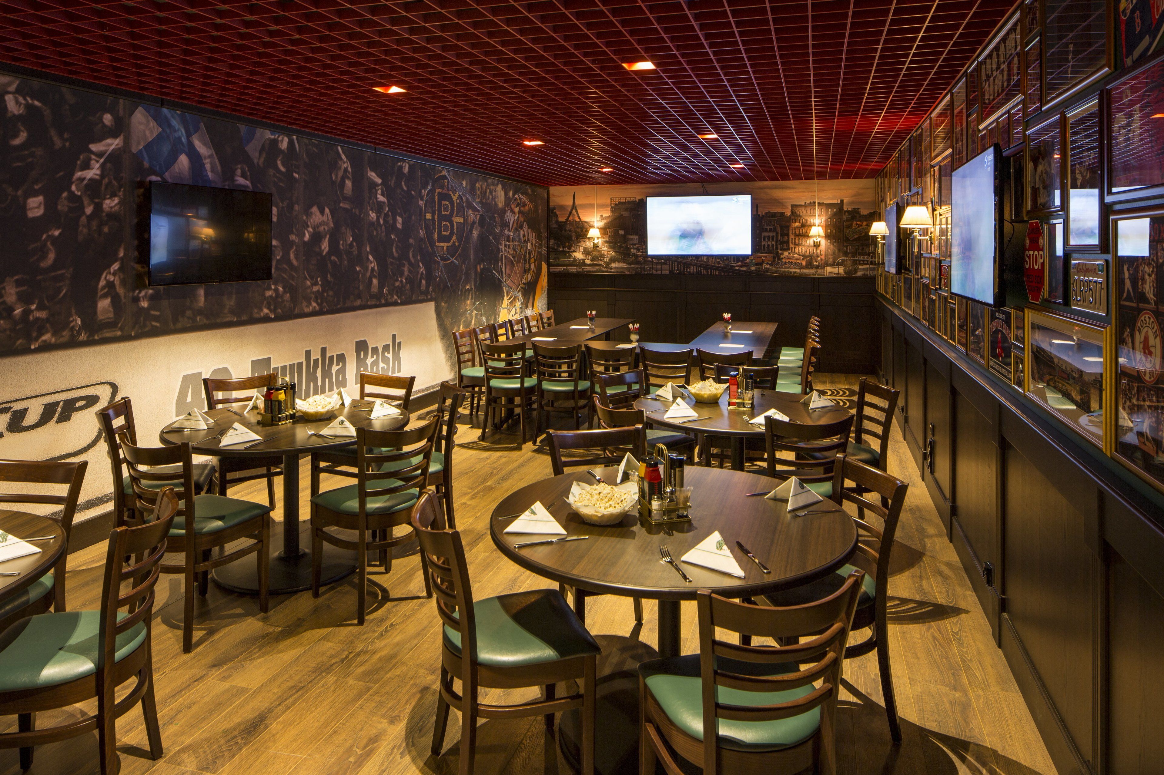 Un restaurant doté de plusieurs tables et chaises rondes, d’un plafond rouge et d’un grand écran diffusant une vue panoramique sur la ville.