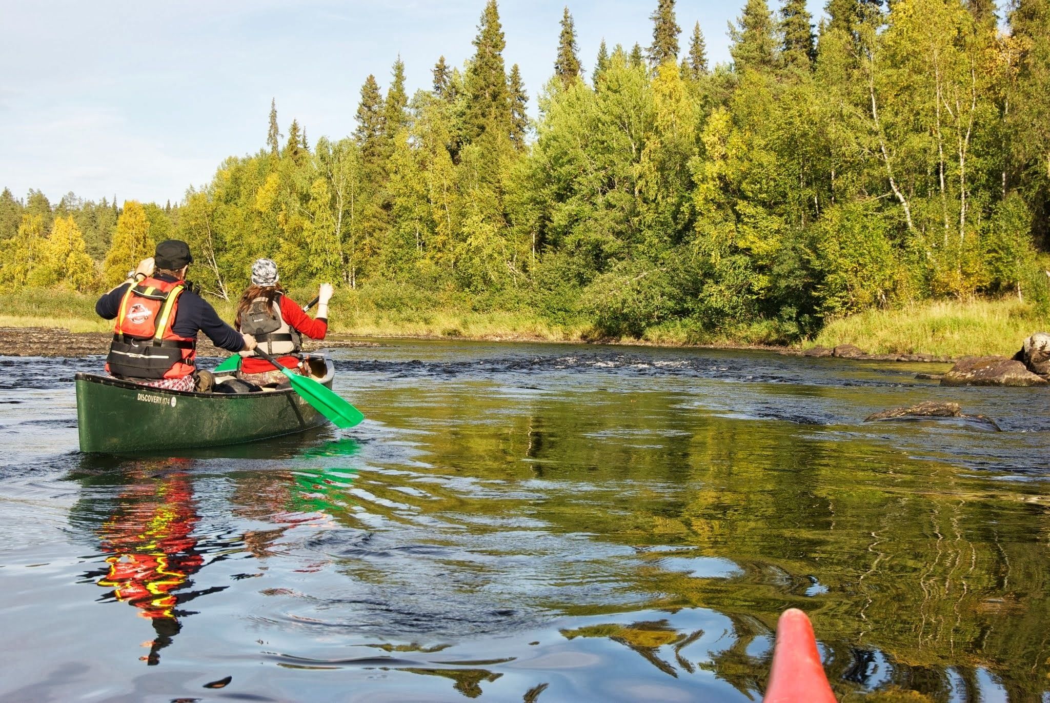 Two people in a canoe on a river surrounded by dense forest.