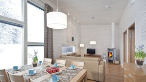 A modern living room with a dining area, large windows, a fireplace, and a television. - Holiday Club Kuusamon Tropiikki (Kuusamo)