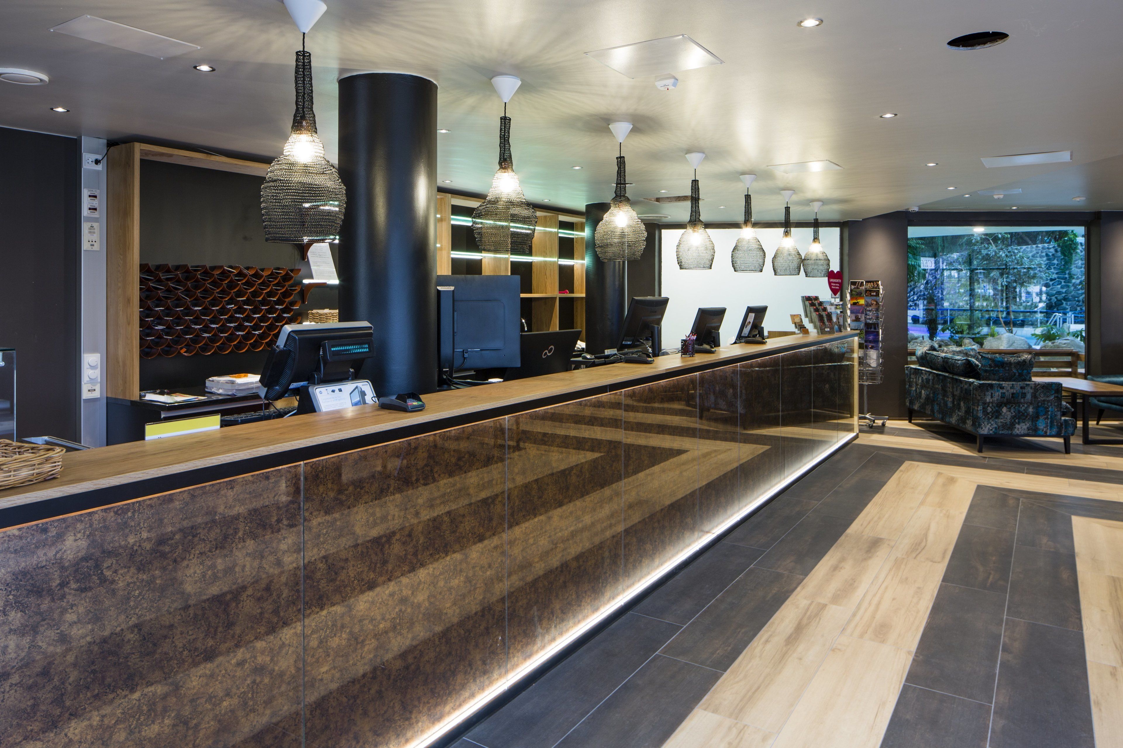 A modern reception area with a long counter, multiple computer stations, and pendant lighting.