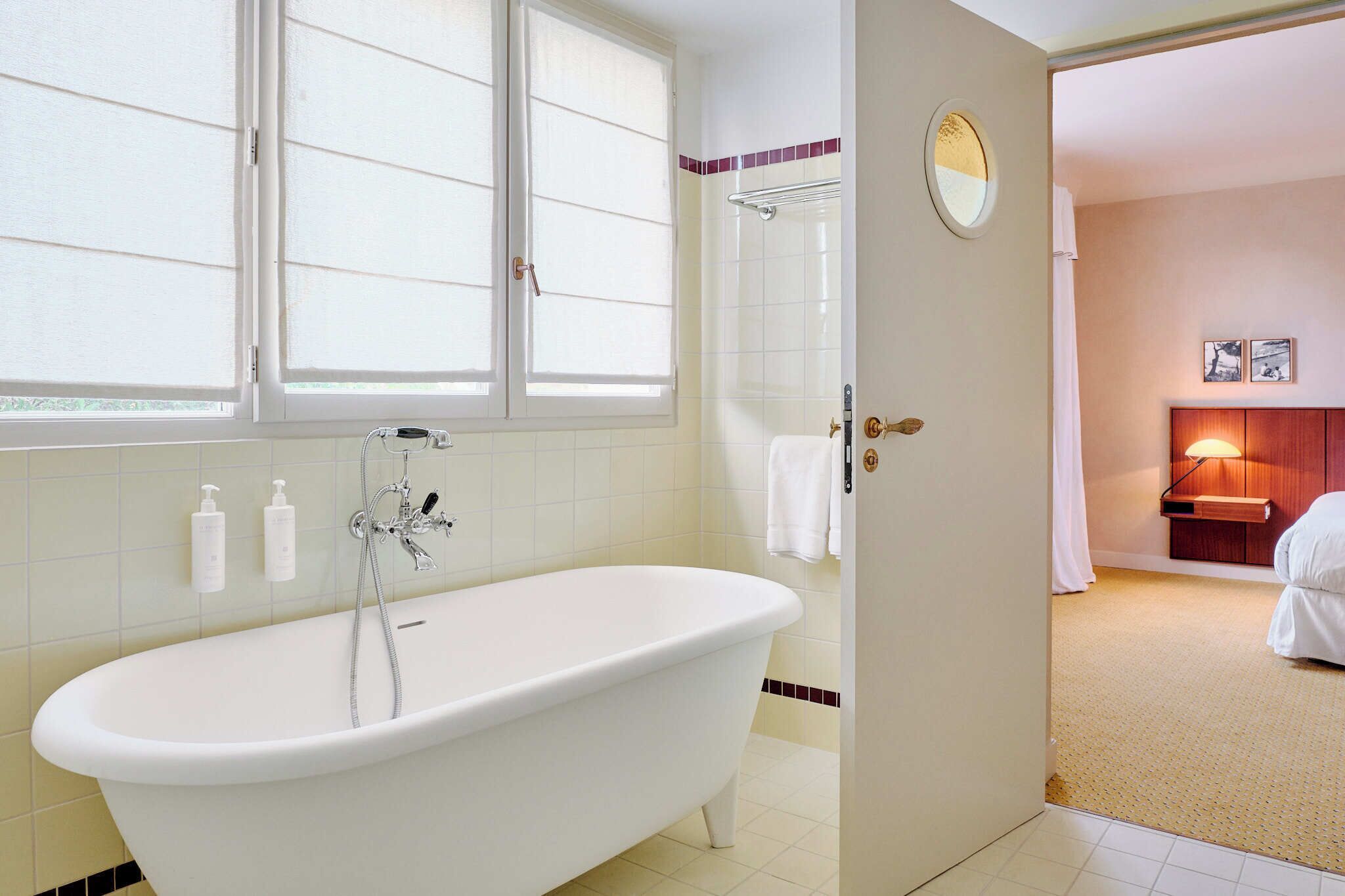 Um banheiro com banheira de imersão, uma janela e uma porta que dá para um quarto.