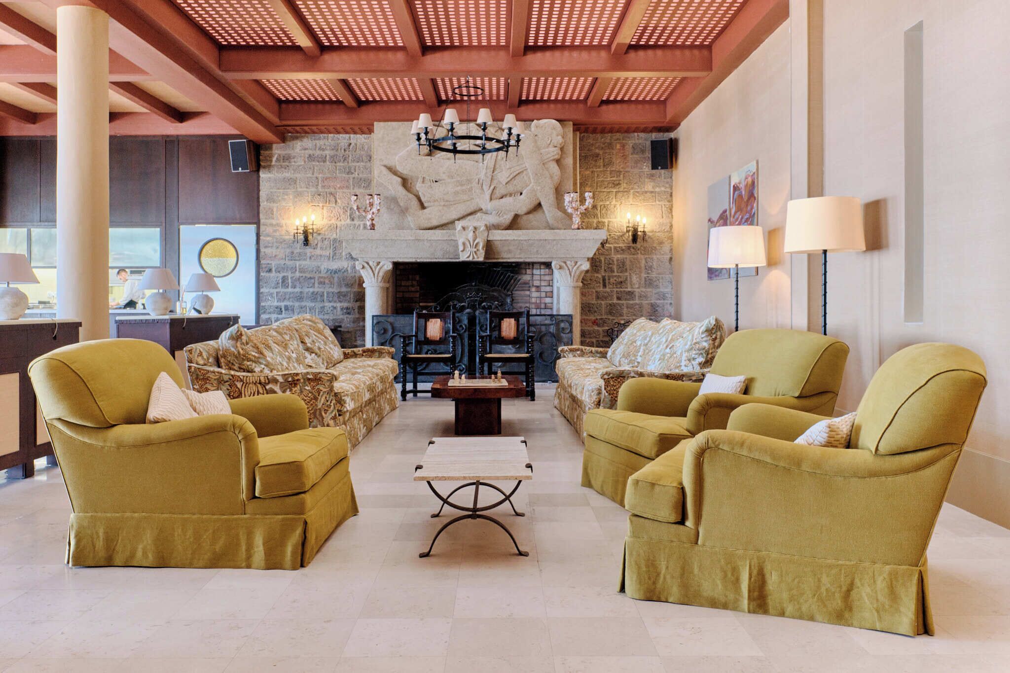 A spacious lobby with a stone fireplace, two yellow armchairs, and a coffee table.