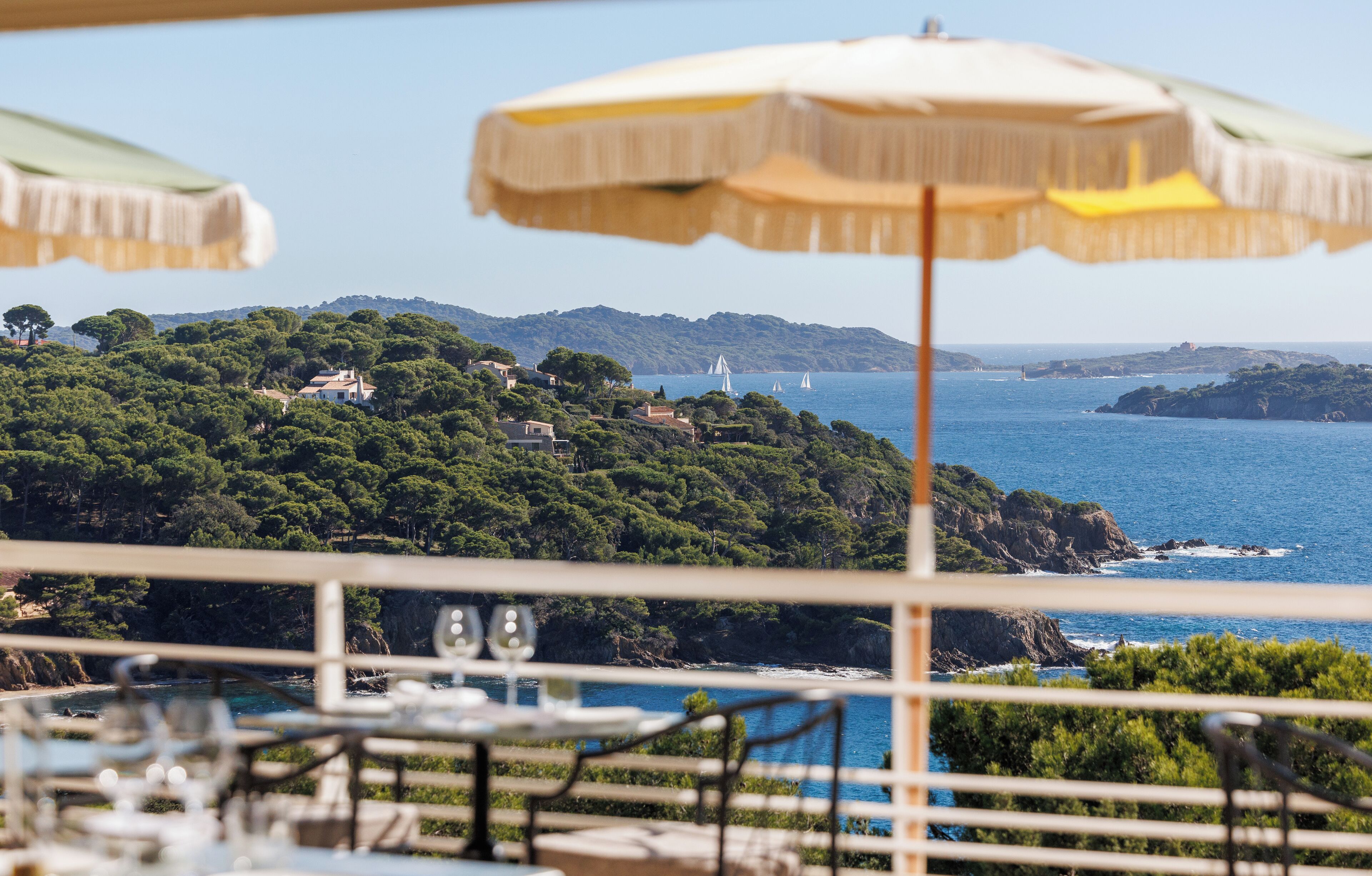 Una terraza con asientos al aire libre, con vistas a un paisaje costero con árboles y el mar.