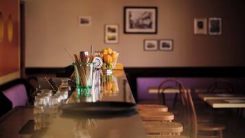 Un espace bar avec un long comptoir, des verres et un panier de fruits.