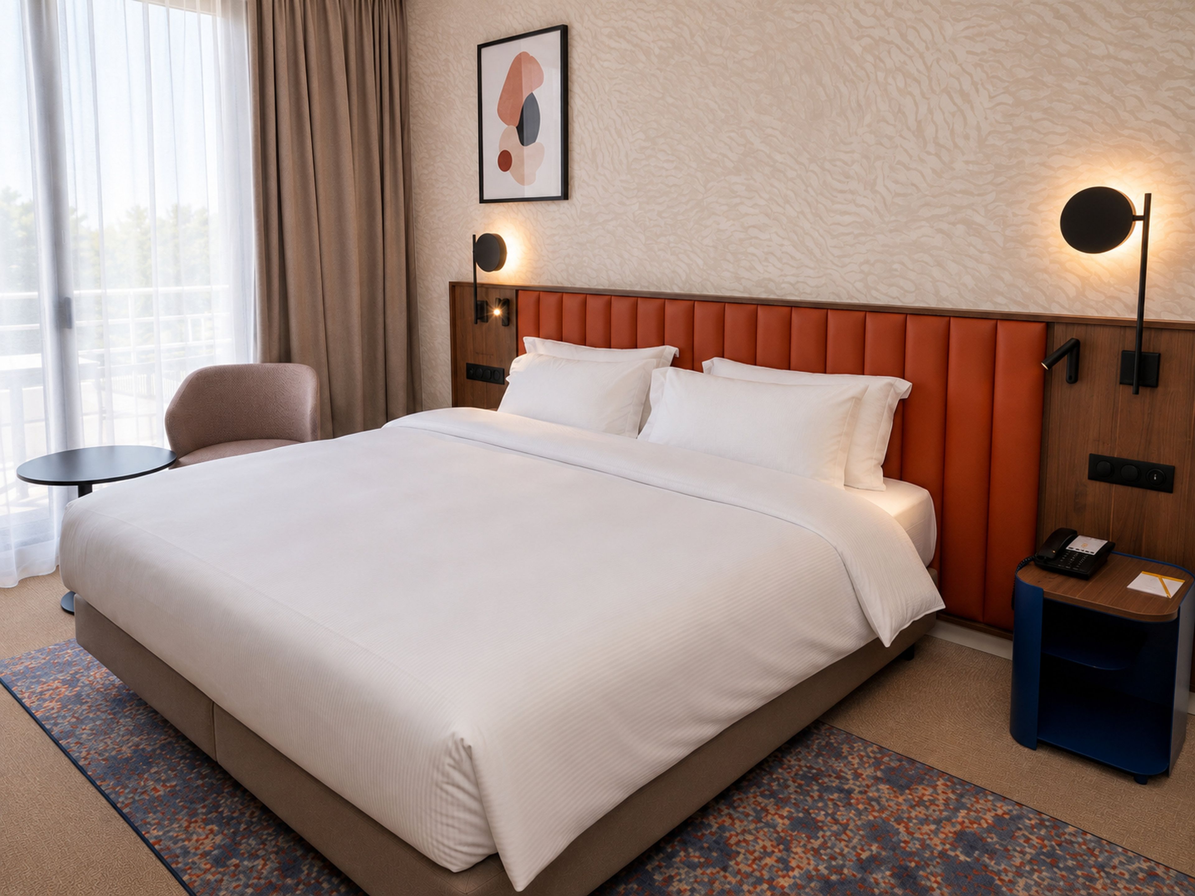 A hotel room with a large bed, a desk, a chair, a nightstand, a lamp, and a painting on the wall.
