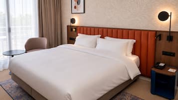 A hotel room with a large bed, a desk, a chair, a nightstand, a lamp, and a painting on the wall.