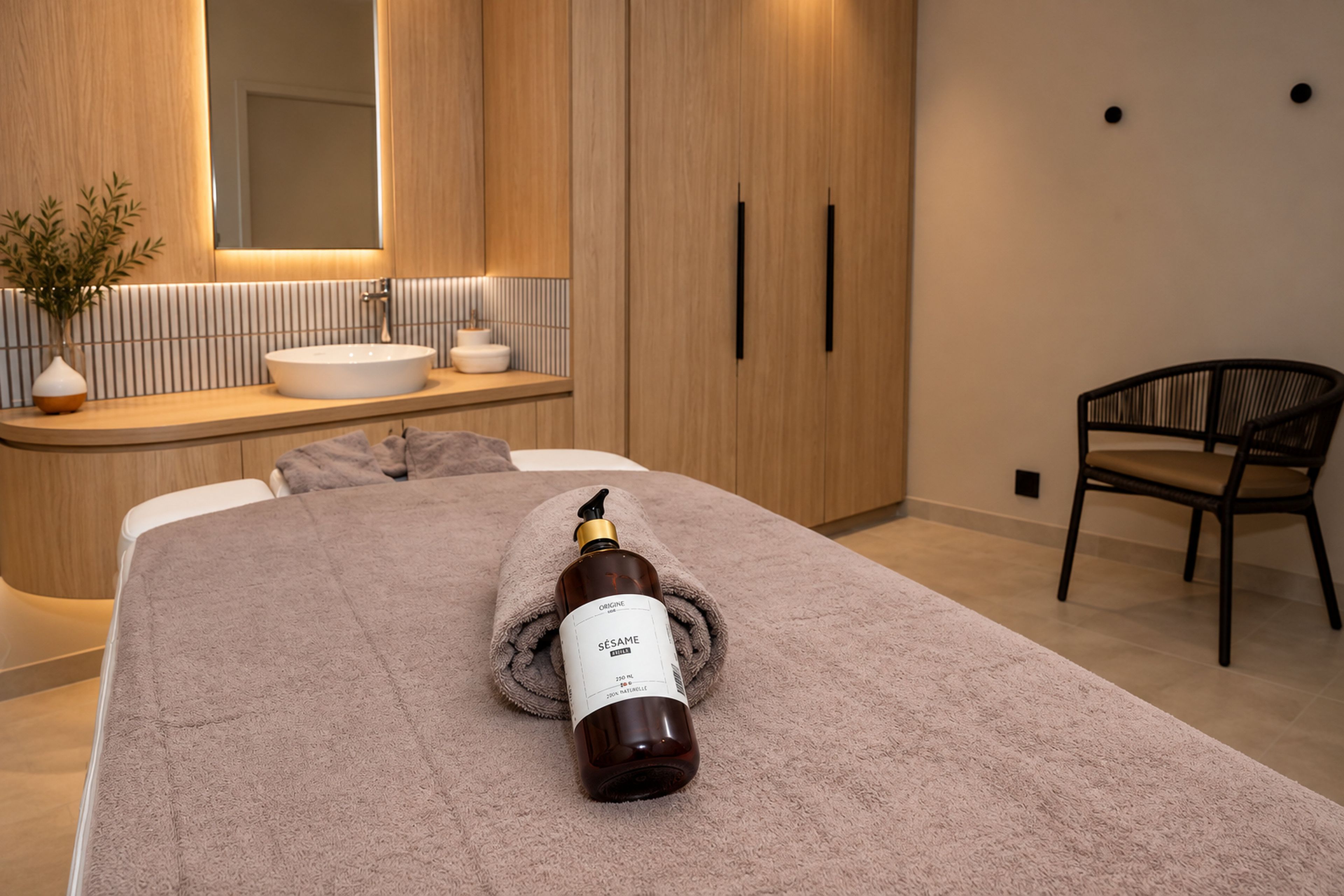 A modern bathroom with a large mirror, wooden cabinets, a sink, and a towel on the floor.